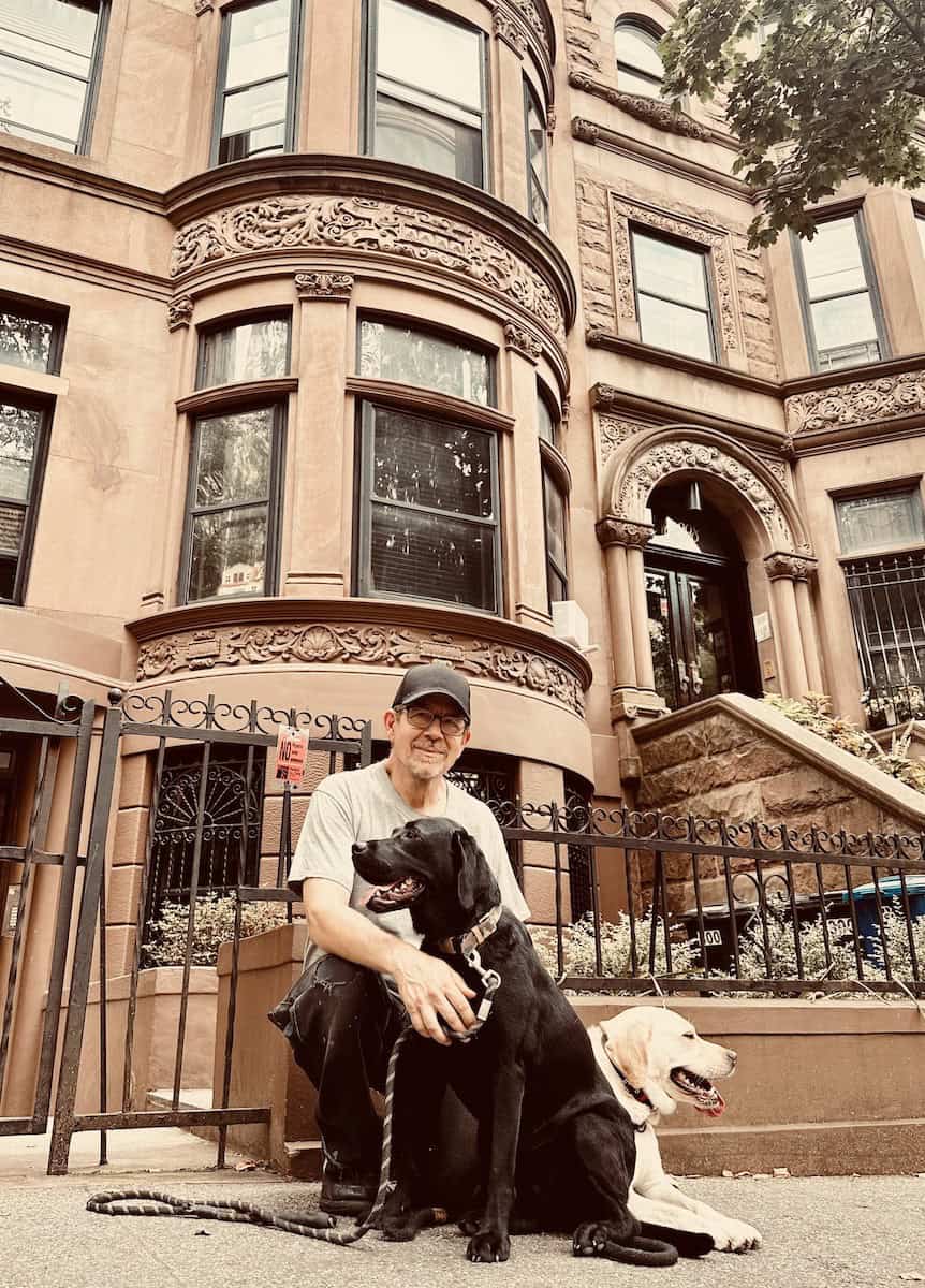 man in front of an apartment building with two dogs